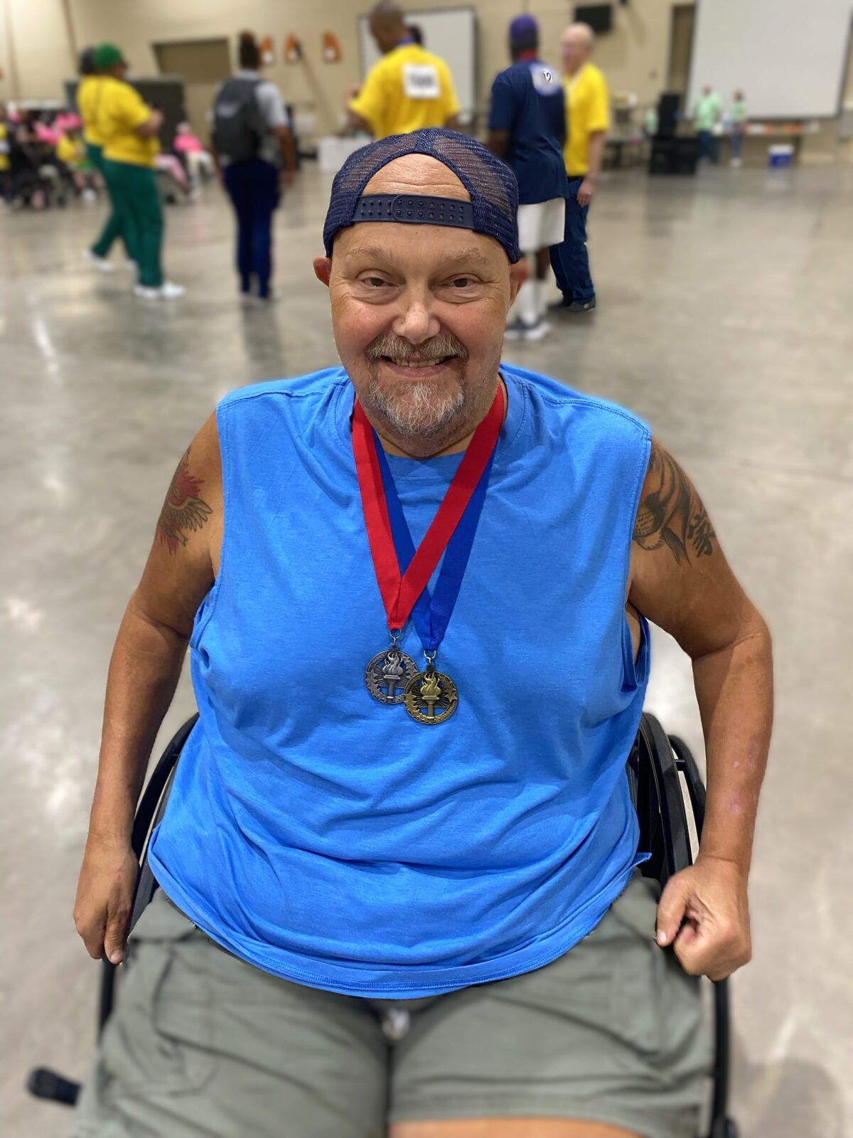 Adult male in wheelchair with two medals around neck.